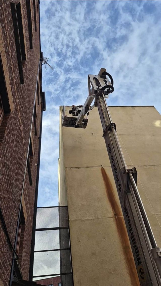 Boom lift raised to a high-level aerial system on a residential building