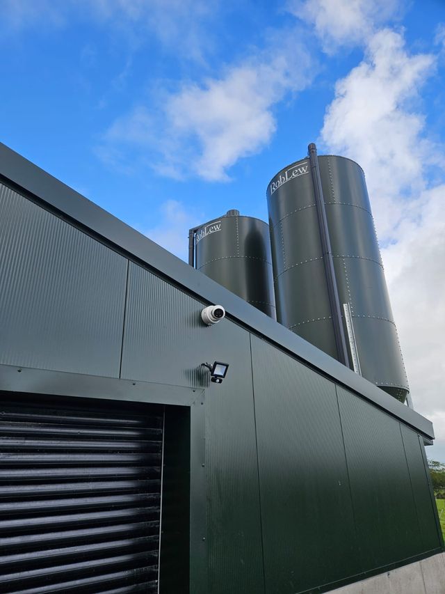 Poultry house with feed silos and a CCTV camera mounted on the outside wall