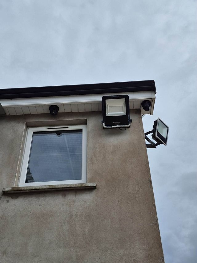 Black turret CCTV cameras on the corner of a house below the gutter