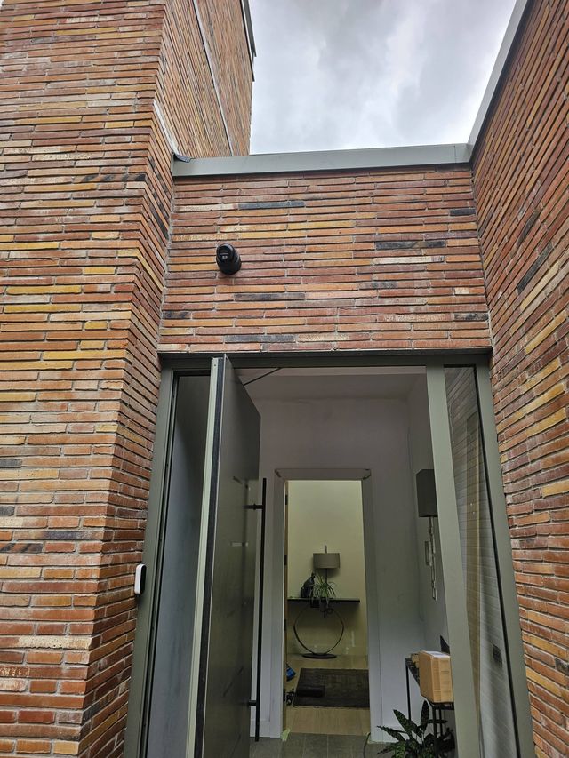 CCTV camera above the entrance of a brick-clad house