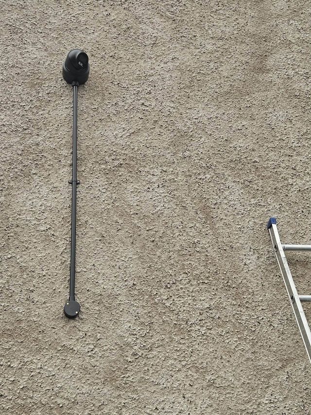 PTZ CCTV camera on a rendered wall with cabling in black conduit