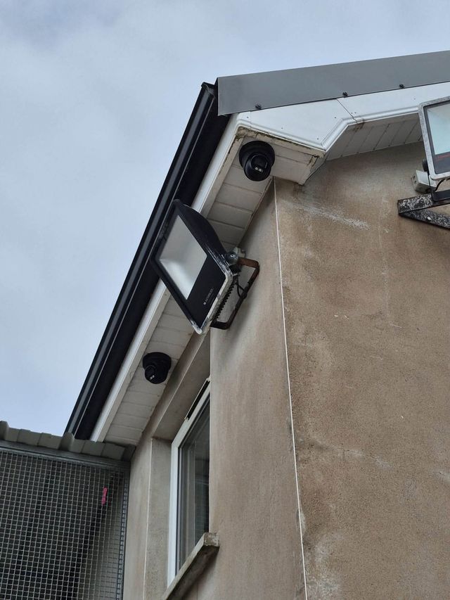 Turret cameras and floodlights on the gable of a house
