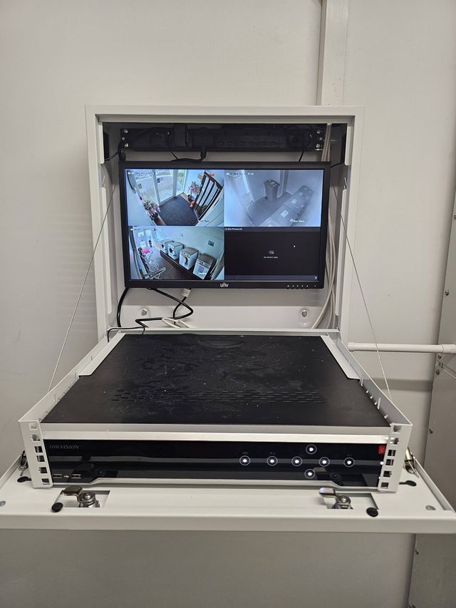 Open lockable CCTV cabinet with a 24-inch monitor showing camera views above the recorder