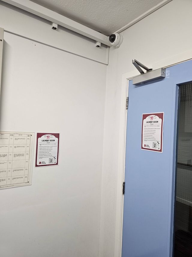 Vandal-resistant dome camera mounted above a doorway in a corridor