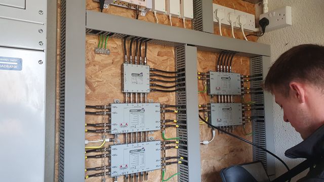 Antenna Systems engineer testing a multiswitch TV distribution system with a signal meter