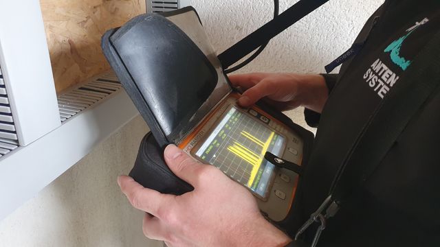 Engineer in an Antenna Systems jacket checking TV signal levels on a spectrum analyser