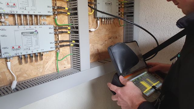 Signal meter connected to a wall-mounted TV distribution panel