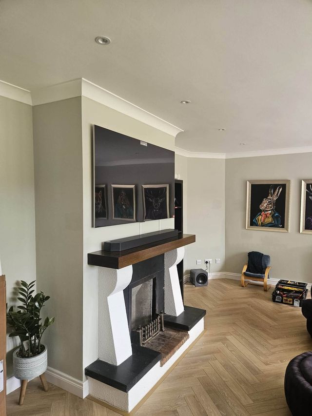Large TV mounted flush on the chimney breast above a fireplace